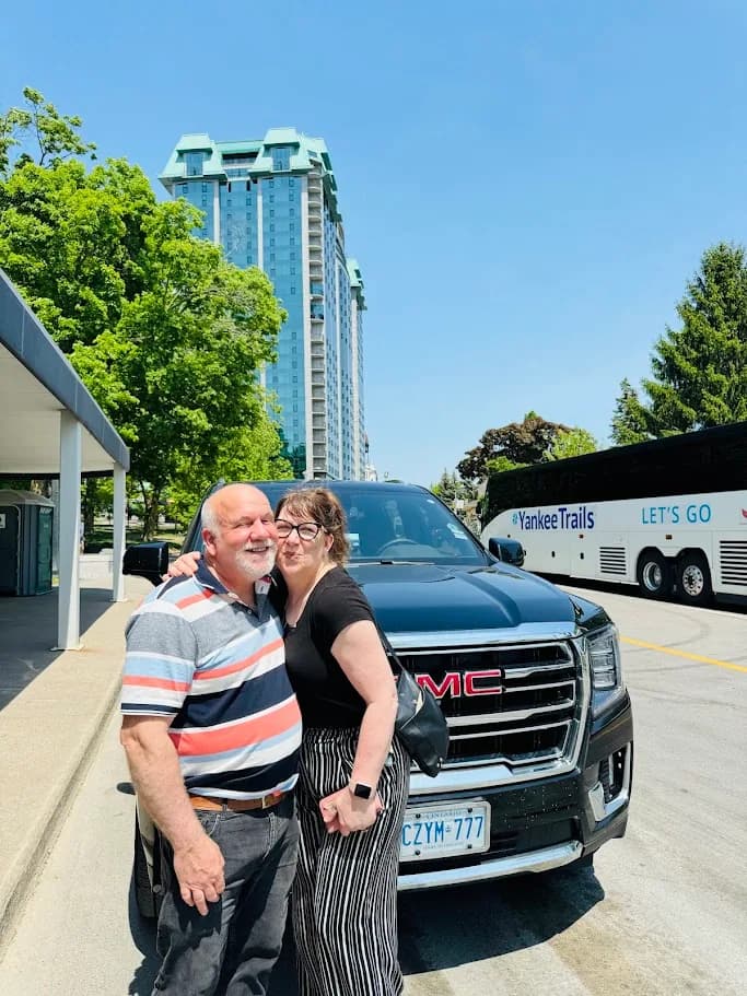 Couple standing together beside a black luxury SUV