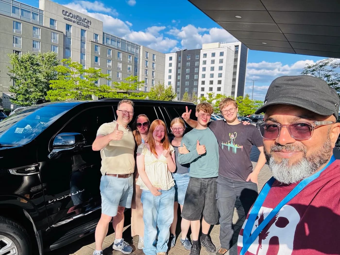 Family group standing beside a private black passenger van