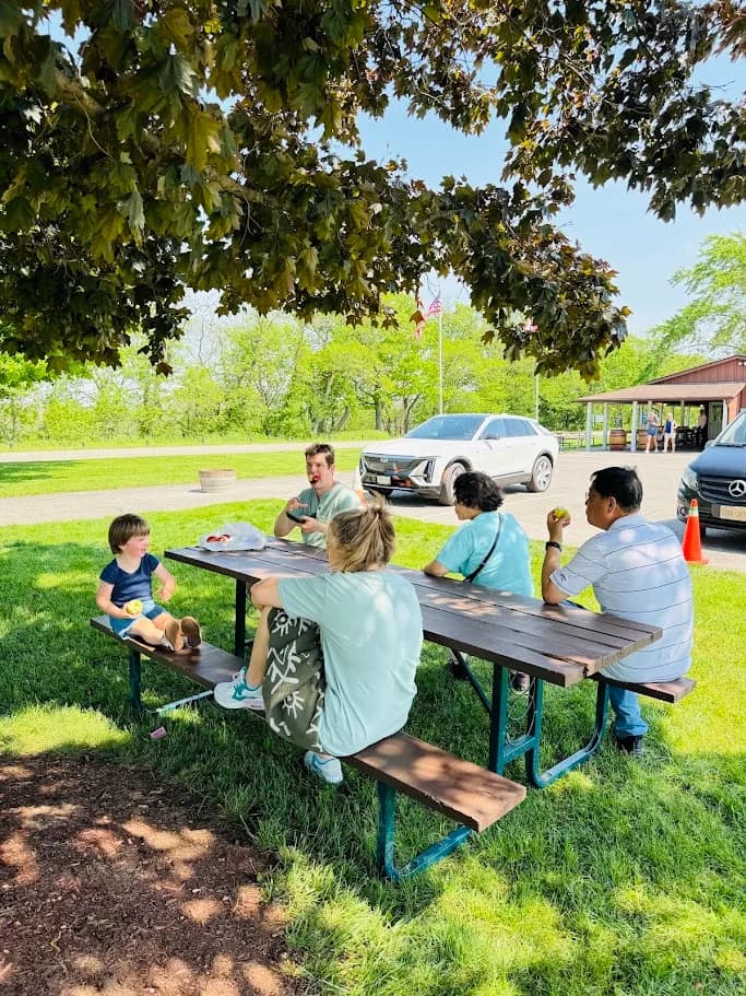 Family group gathered at a shaded picnic table during a tour stop
