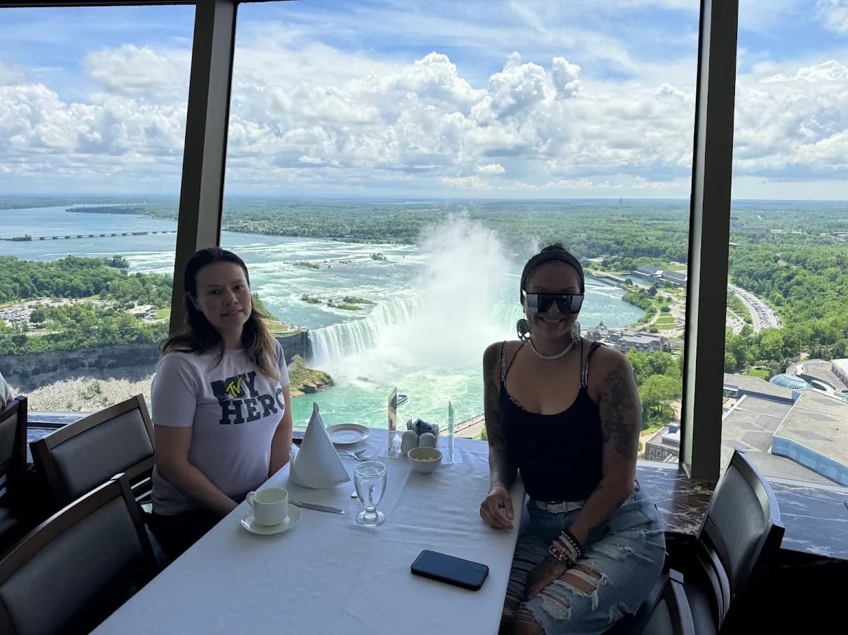 Guests seated at a restaurant table with Niagara Falls visible through the windows