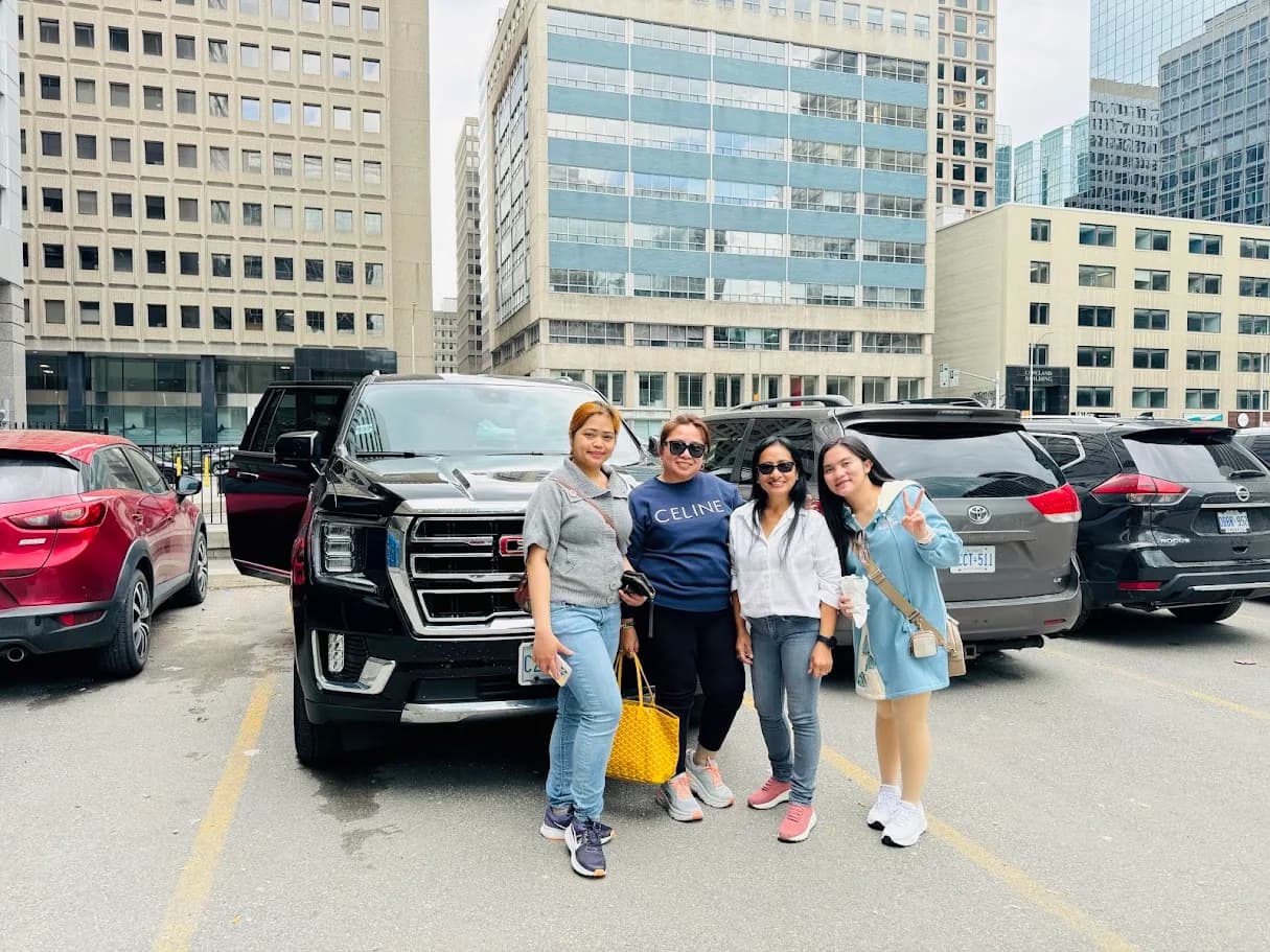 Group of guests standing beside a black SUV in a city pickup area