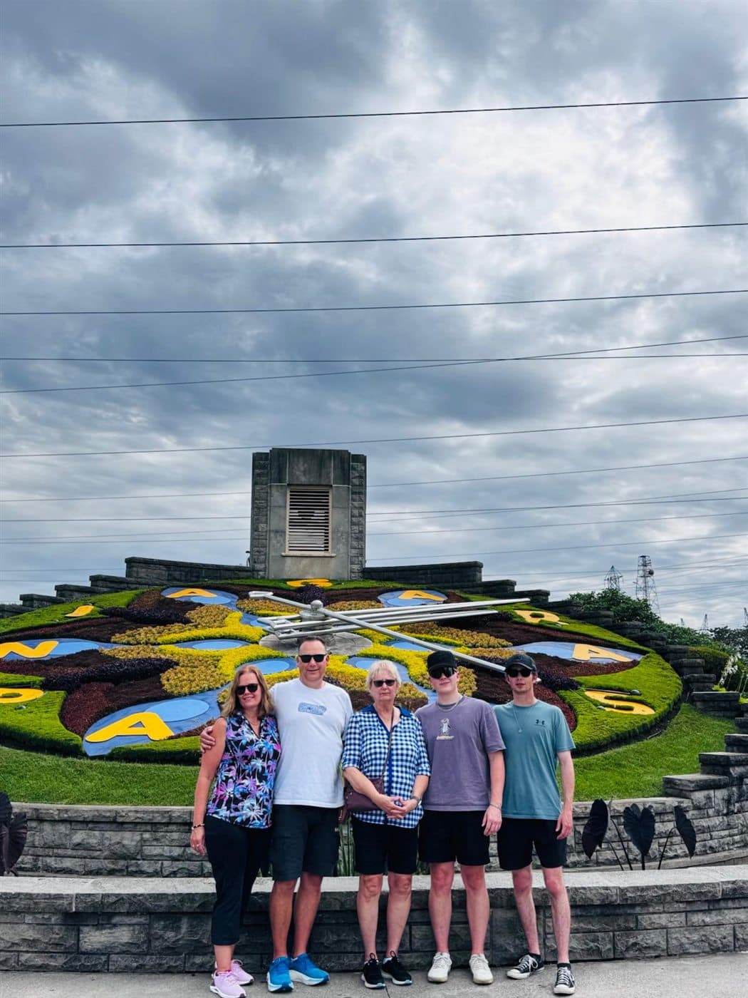 Family group standing in front of the Niagara Parks Floral Clock under a cloudy sky