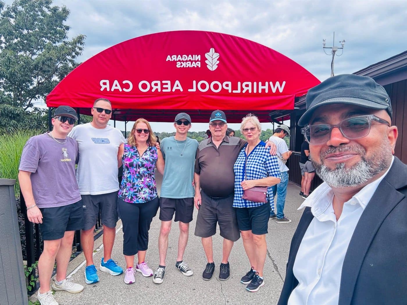 Tour group and chauffeur posing near the Whirlpool Aero Car during a Niagara private tour