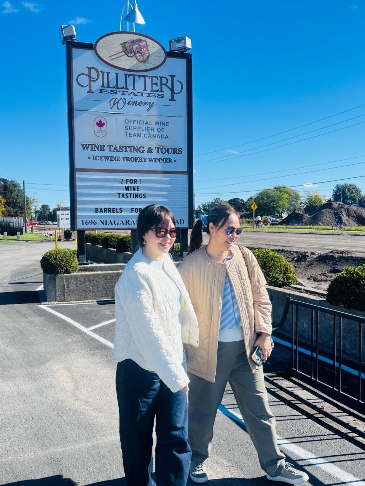 Guests posing near the Pillitteri Estates Winery sign on a sunny Niagara wine tour