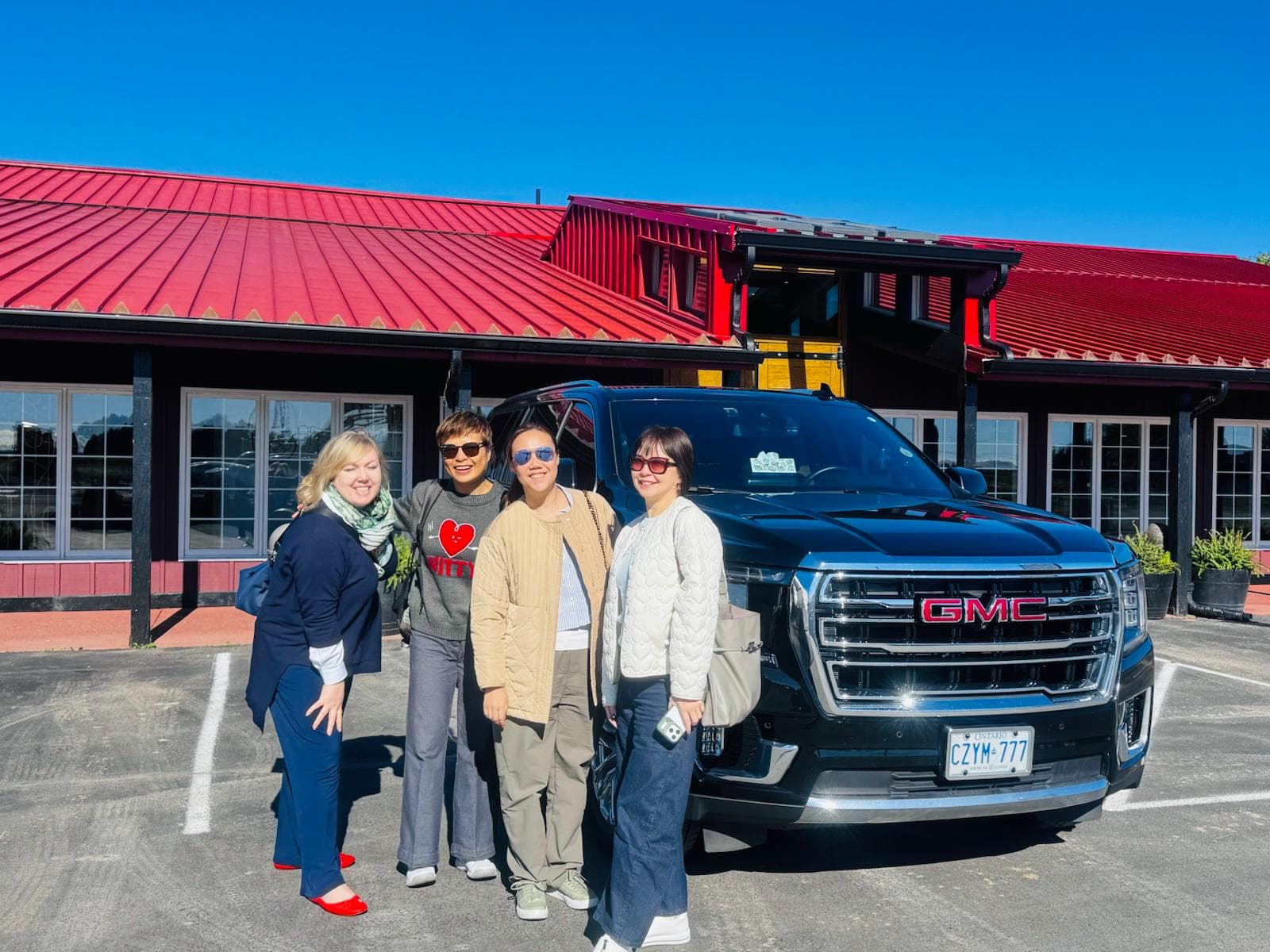 Private wine tour guests standing beside a black GMC SUV outside a Niagara winery